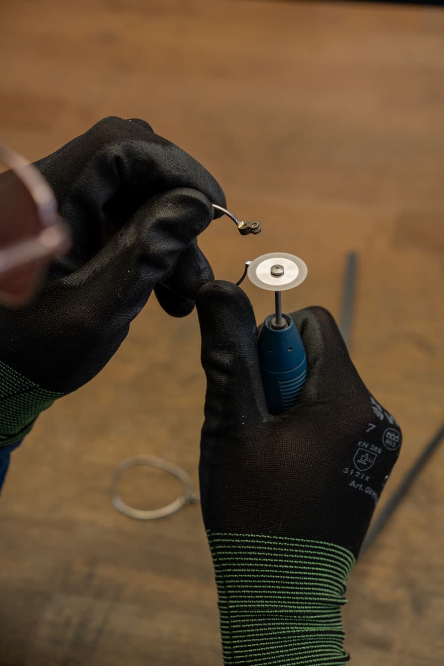 Ein Lunor Mitarbeiter schleift mit einem Elektrowerkzeug überschüssiges Lot von einem Brillenhalbteil,